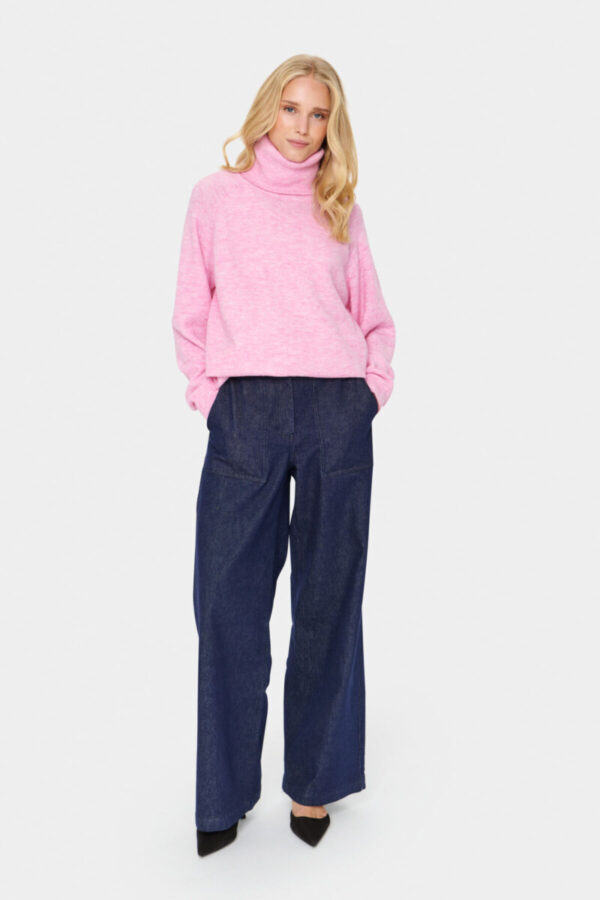 Blonde Frau in einem rosa melierten Rollkragenpullover kombiniert zur Jeans