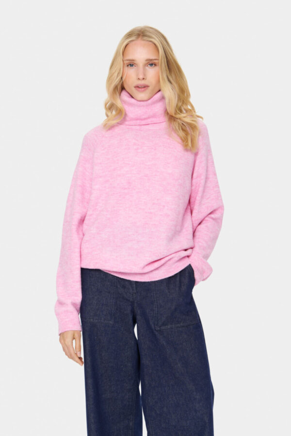 Blonde Frau in einem rosa melierten Rollkragenpullover kombiniert zur Jeans