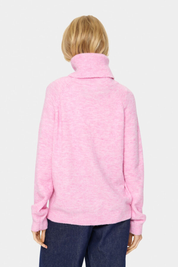 Blonde Frau in einem rosa melierten Rollkragenpullover von hinten