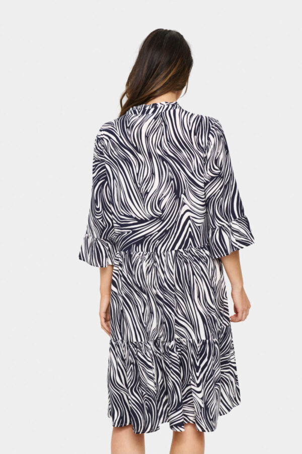 Kurzes Kleid mit abstraktem Print in Off-White und Marineblau, locker geschnitten. Mit V-Ausschnitt, ellbogenlangen Ärmeln und leicht ausgestelltem Saum. Aus weichem Webstoff gefertigt. Das Model ist 175 cm groß und trägt Größe S.